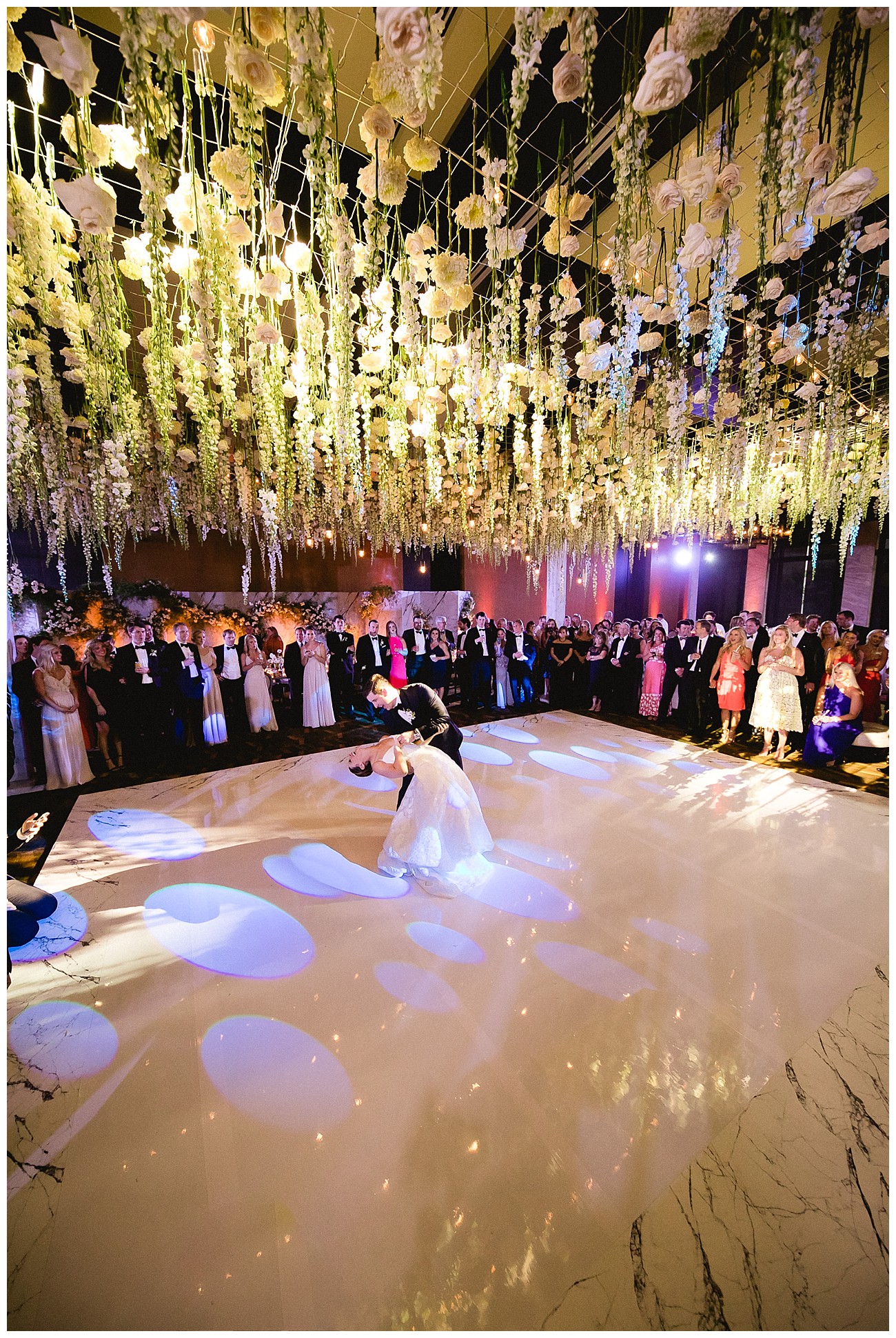 bride and groom doing their first dance under a stunning floral arrangement at white floral theme for a wedding at JW Marriott San Jose del Cabo
