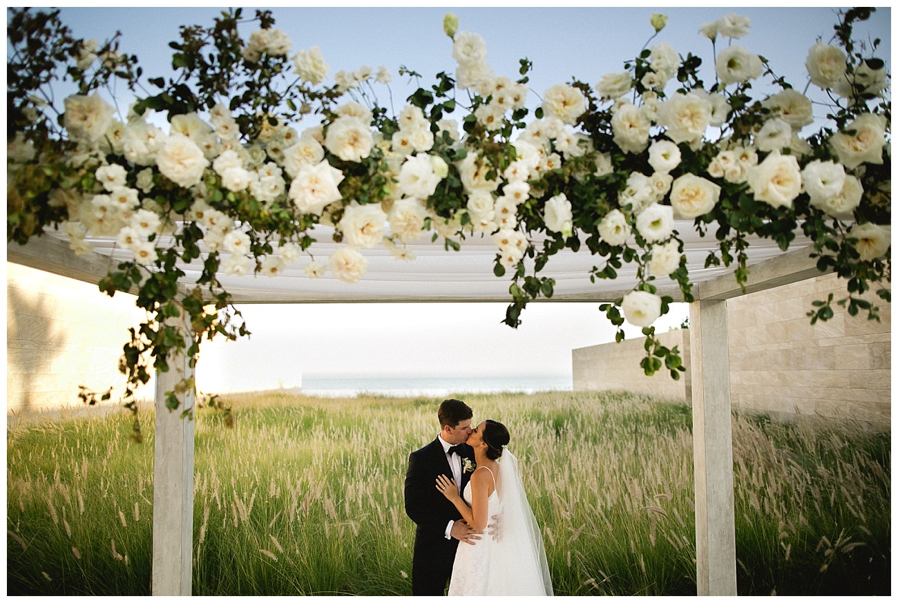 under an arbor of white roses at wedding at JW Marriott San Jose del Cabo