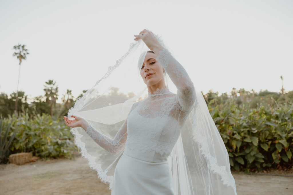 bride on her wedding day holding out her veil